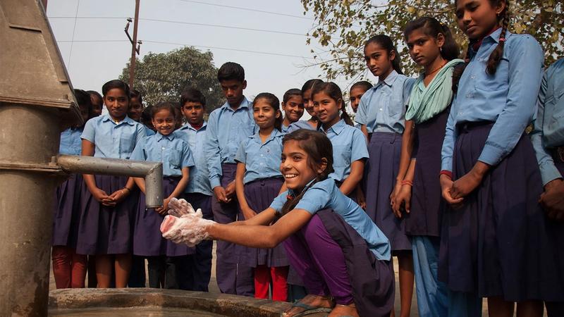 School children washing their hands at an outdoor fountain