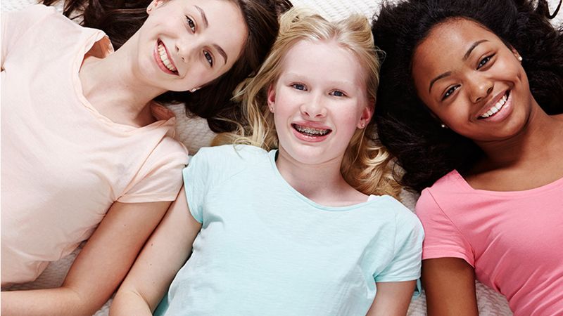 Three girls smiling. Dove’s Self Esteem Project empowers young people to improve their body confidence through education.