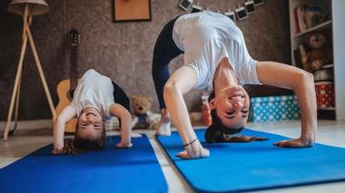 Mother and daughter stretching in yoga mat