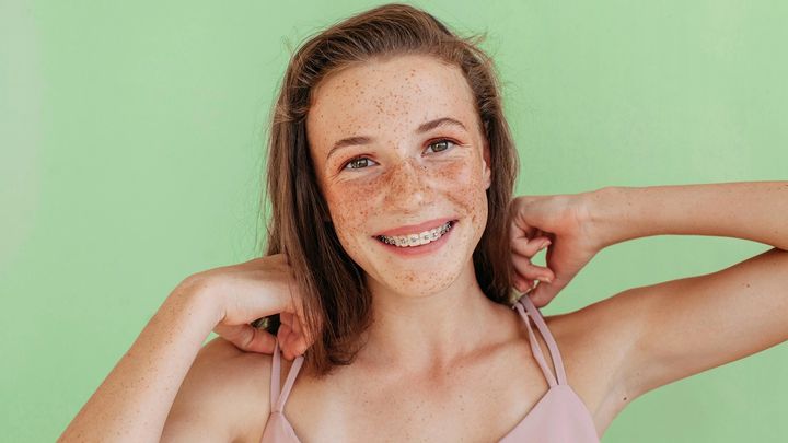 Young girl on a green background smiles directly at the camera