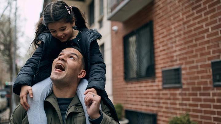 Man laughing with daughter on shoulders