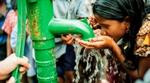 Girl cupping her hands and drinking clean, safe water from a community tap 