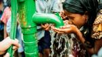 Girl cupping her hands and drinking clean, safe water from a community tap
