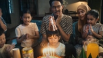 A photo of a family at a birthday party. The father is clutching his jaw in pain from toothache.