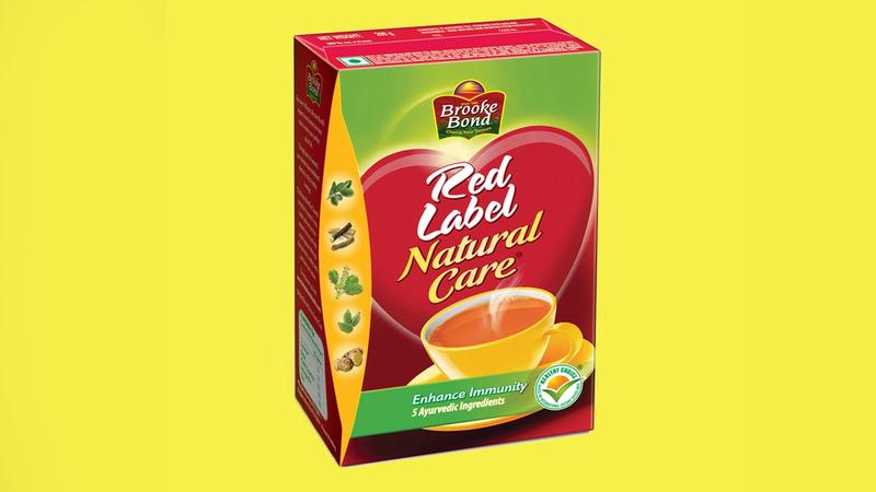 A box of Brooke Bond Red Label Natural Care tea against a yellow background