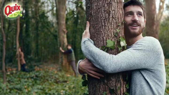 A static shot from a Quix television advert. The photograph features a man hugging a tree.