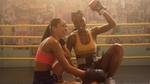 Two female boxers sitting in a boxing ring