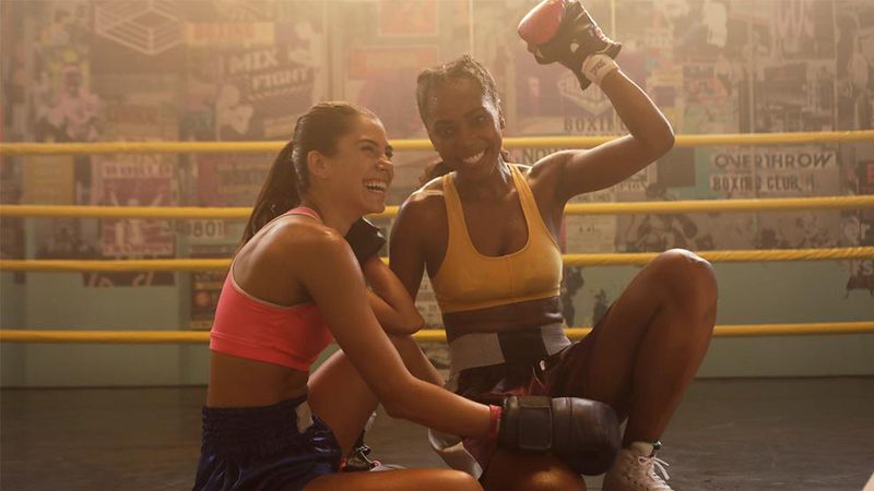Two female boxers sitting in a boxing ring