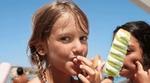 Close-up of a young girl on a beach eating a green and white ice lolly