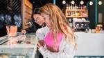 Two friends choosing an ice cream from a retail ice cream cabinet