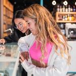 Two friends choosing an ice cream from a retail ice cream cabinet