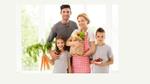 Family of mother and father with two children holding bag of groceries with fruits & vegetables