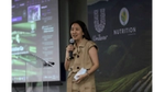 Kristine Go speaking with a micropone. Behind her are the Unilever and Nutrition Southeast Asia logos