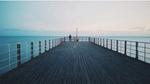 An image of a person on a pier looking out to the sea