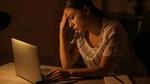 A picture of a lady in front of her laptop working in a dim light set up