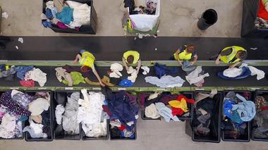 Four people sorting clothes on a conveyor belt