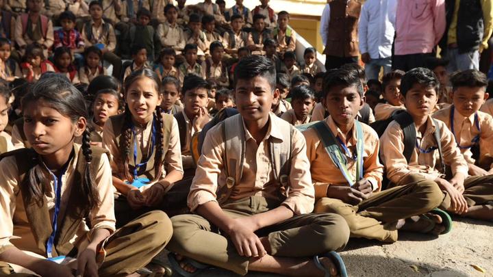 A group of schoolchildren sitting on the ground. Unilever works with UNICEF to improve sanitation in schools.