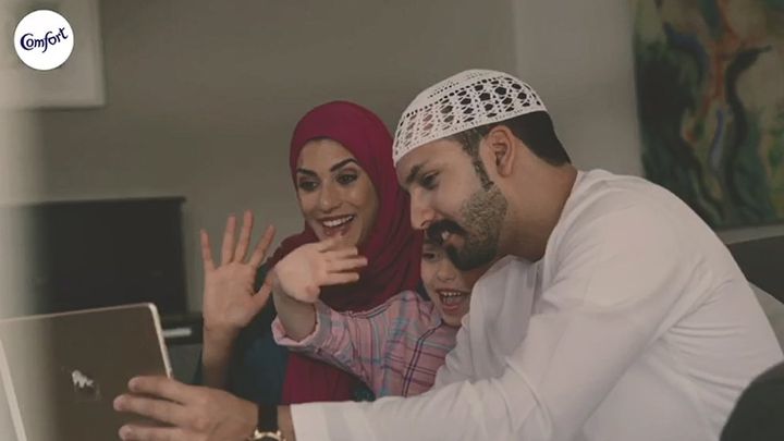 Still from TV ad showing a mother, father and child making a video call on a laptop.