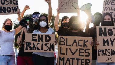 A group of people at a Black Lives Matter protest holding cardboard signs 