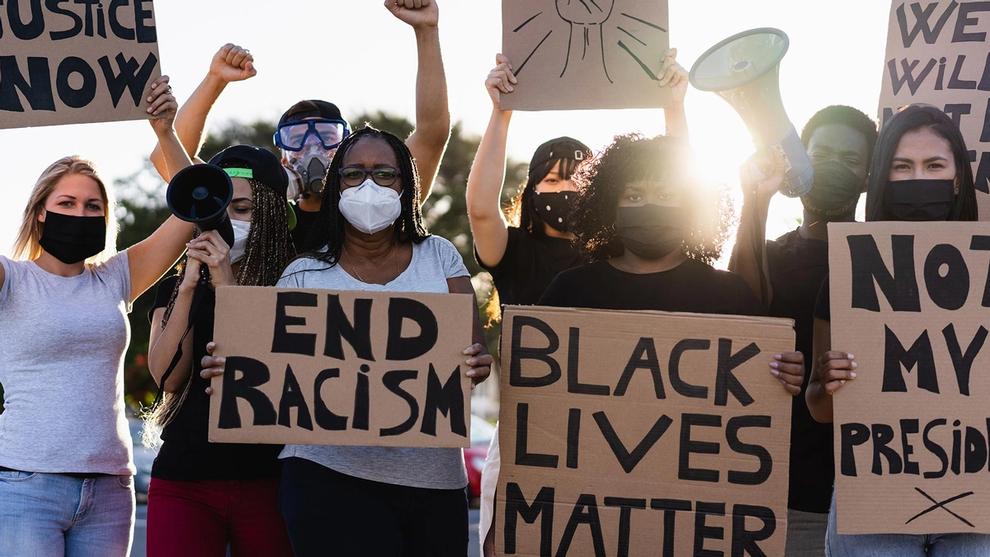 A group of demonstrators hold up posters calling for an end to racism
