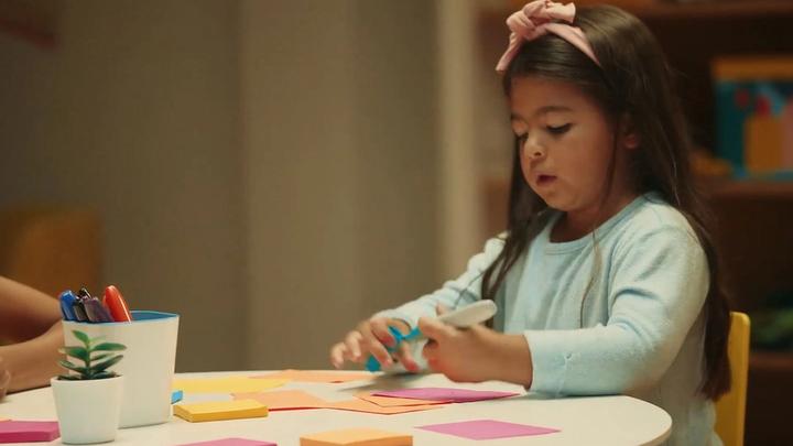 A photograph of a child writing something on a piece of paper.