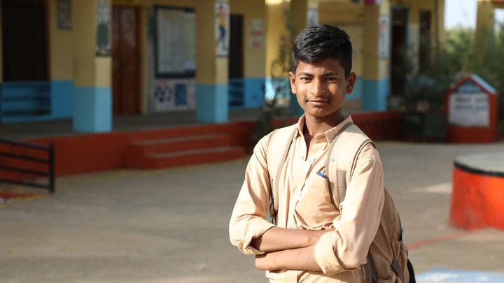A young boy stands outside school toilets in India