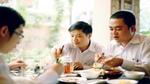 Three Vietnamese businessmen sit round a table to enjoy lunch together