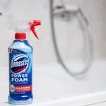 The new Domestos Power Foam Spray bottle sits on the edge of a white toilet