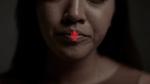 Close up of a woman's face with a red mute button on her lips 