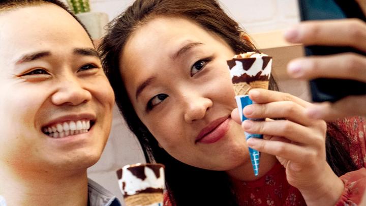 A man and a woman holding Cornetto ice creams while taking a selfie