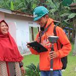 Woman smallholder laughs while talking to surveyor during Unilever palm plantation mapping project