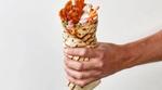 A close-up of a hand holding a plant-based döner kebab wrap