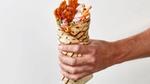 A close-up of a hand holding a plant-based döner kebab wrap