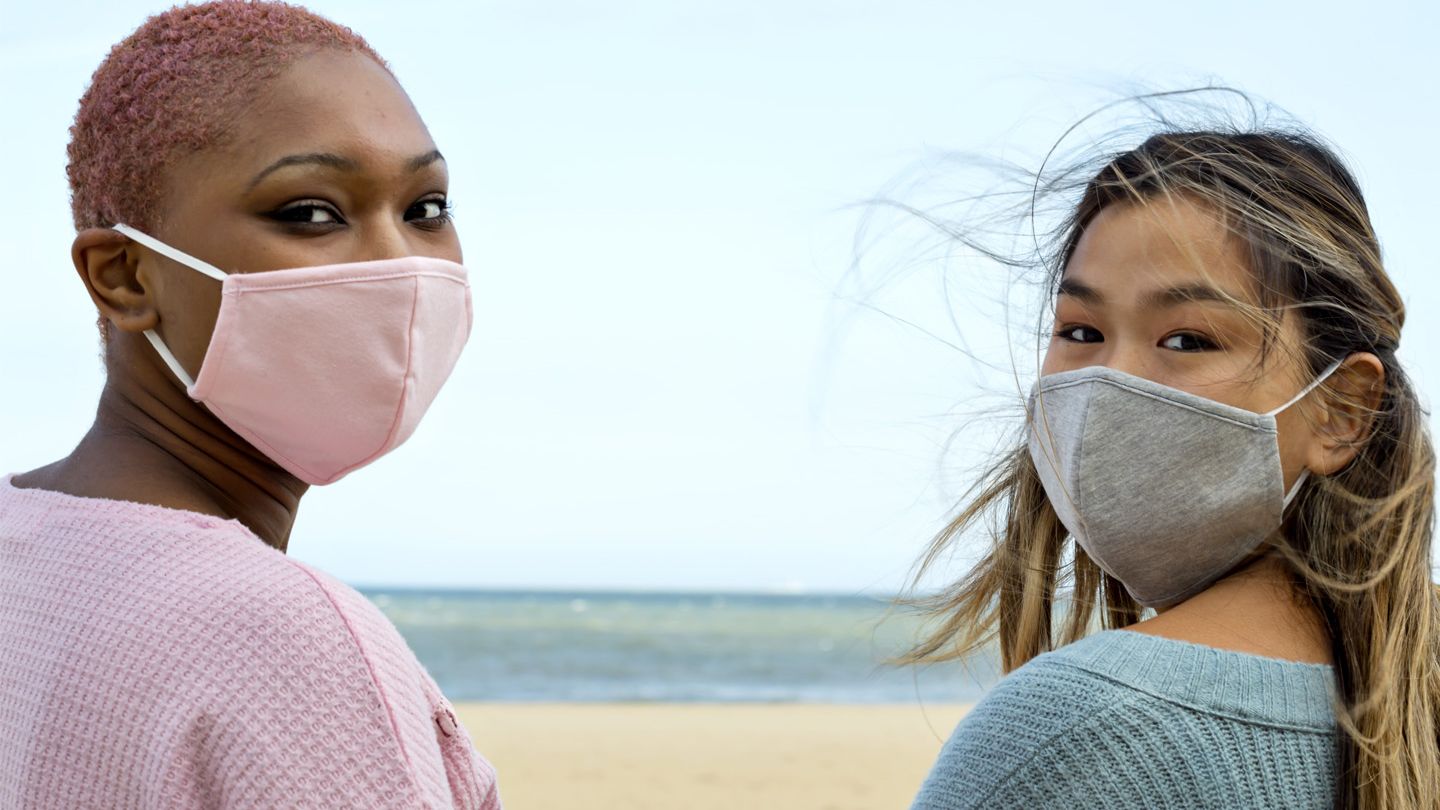 Two people wearing facemasks, one pink and one wearing grey.
