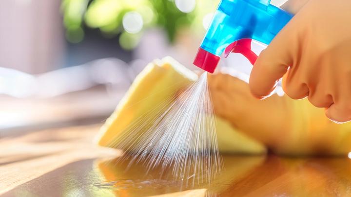 Close up of a cleaning product being sprayed and wiped down on a kitchen surface