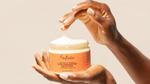 Close up of a Black woman’s hands as she dips fingers into a jar of Shea Moisture Curl Enhancing Smoothie hair product