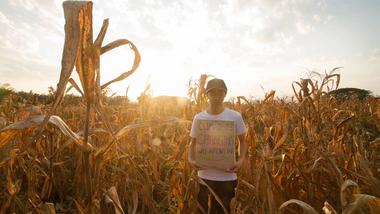 Boy holding a sign in a field of crops