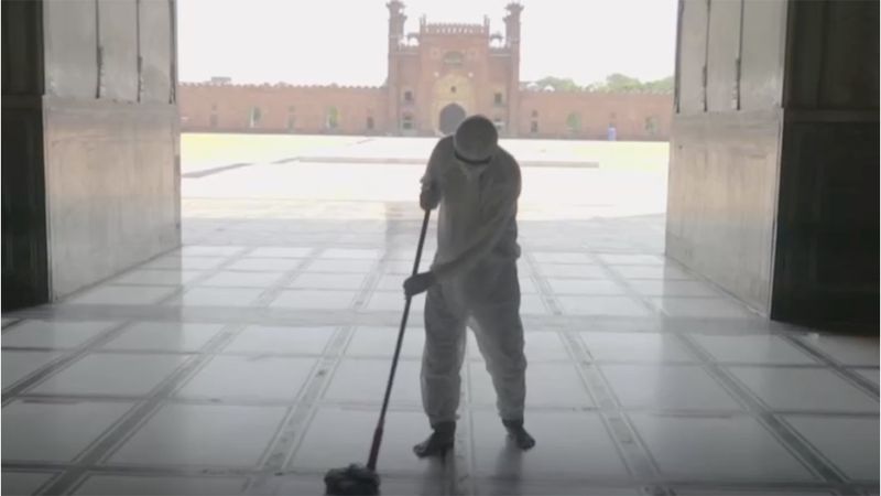 Man mopping the entrance to a large building, using Domestos