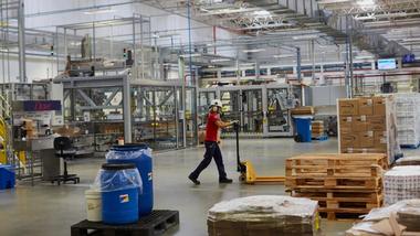 A person wearing a hardhat pushes a trolley across a factory floor
