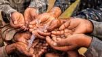 Children bring their hands together to hold some flowing water.