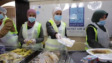 Four people serving food wearing masks