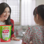 A woman in a red jacket, stands with a pack of Lifebuoy dishwash liquid. A girl is in the foreground facing her.