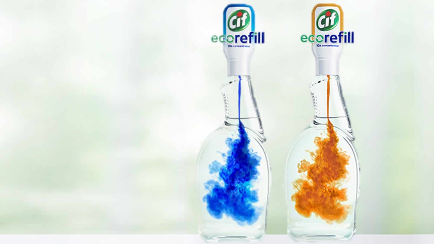 Two bottles of Cif Eco_Refill on a kitchen counter. The concentrated formulas are being diluted into water to refill reusable spray bottles.