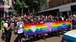 People marching in the road, holding rainbow banner saying Croydon Pridefest