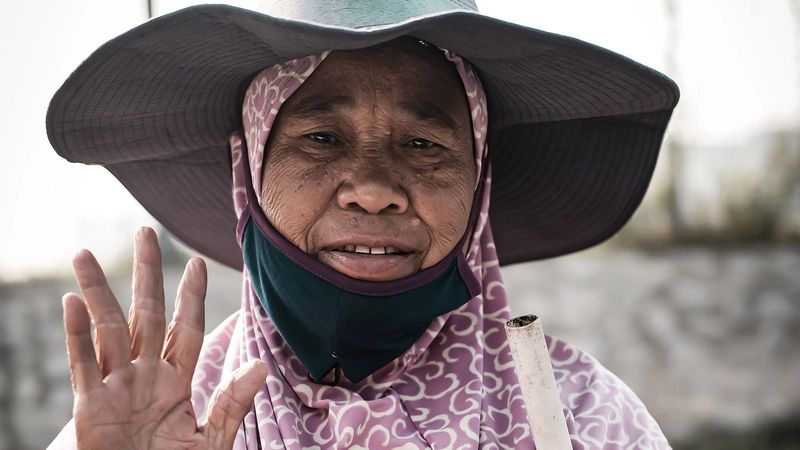 Middle aged woman in a hat holding her hand up to show her palm