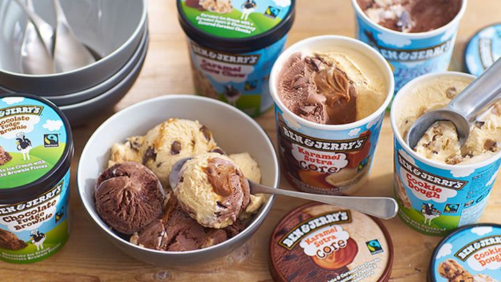 Various tubs of Ben & Jerry’s ice cream with several scoops in a bowl.