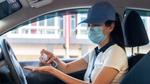 Female driver wearing face mask and cleaning hands with sanitiser. Unilever provides hygiene kits to Uber drivers and couriers.