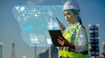 Woman in a hard hat with factory in the background with computer graphics overlaid on the image