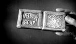 A black and white image of a hand holding an original Lifebuoy bar of soap