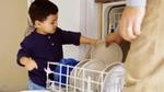 Young child helping to load dishes into a dishwasher
